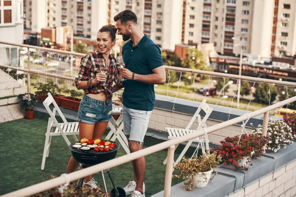 jovem casal fazendo churrasco na varanda que foi personalizada - um dos benefícios de construir sua propria casa