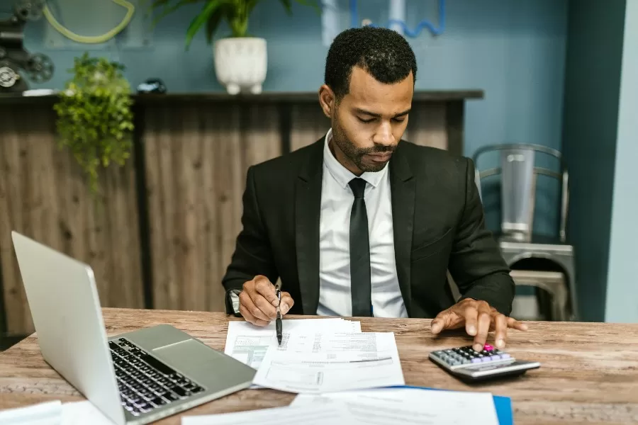 Homem usa calculadora e planilhas para realizar precificação